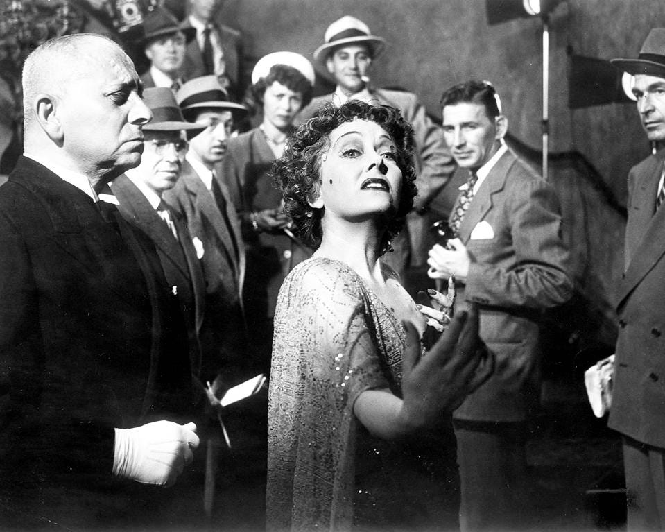 Norma Desmond stoi w korytarzu obok drzwi